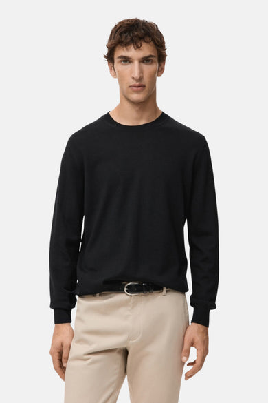 Zwarte rondehals trui van MANGO, achterkant, gedragen met een beige chino broek.