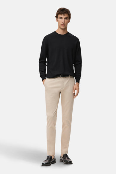Zwarte rondehals trui van MANGO, gedragen met een beige broek en zwarte loafers.