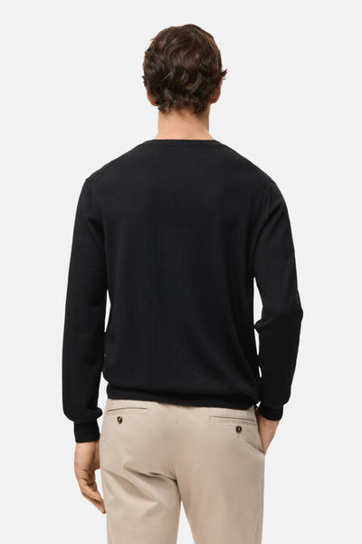 Pull à col rond noir de MANGO, vue de dos, porté avec un pantalon chino beige.