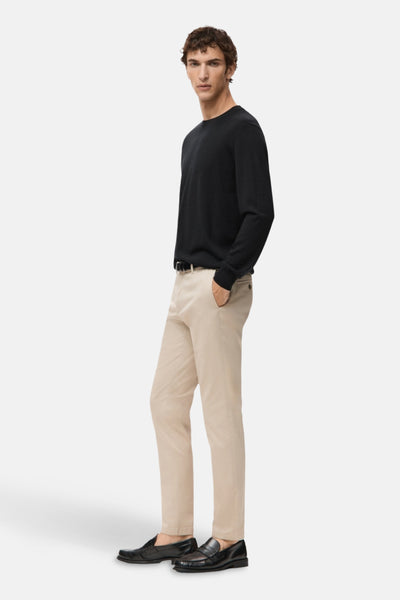 Zwarte rondehals trui van MANGO, gedragen met een beige broek en zwarte loafers.