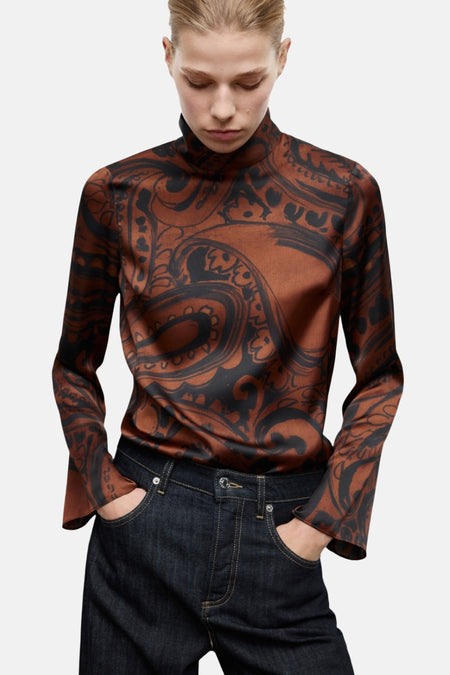 Blouse marron à manches longues de MANGO, à motif cachemire noir, portée avec un jean bleu foncé.
