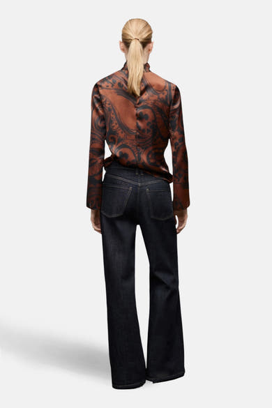 Chemisier à manches longues marron de MANGO, motif paisley noir, porté avec un jean bleu foncé.