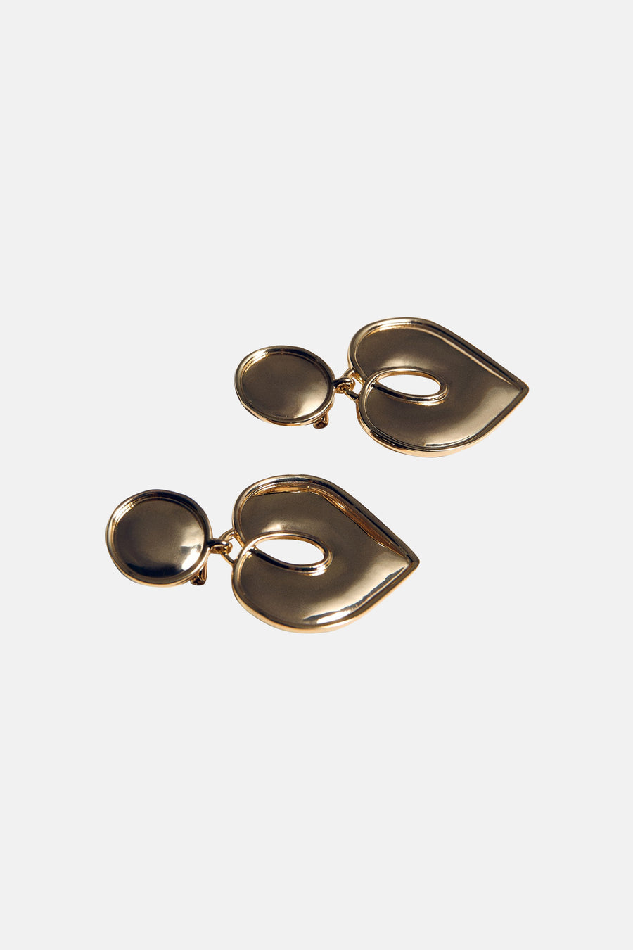Boucles d'oreilles dorées par MANGO, en forme de lèvres avec détail ajouré, sur fond uni.
