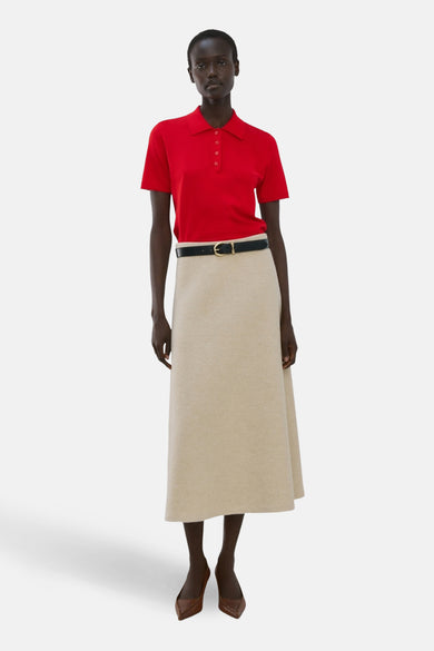 Rode polo met korte mouwen van MANGO, gedragen met een zwarte riem en een beige rok.