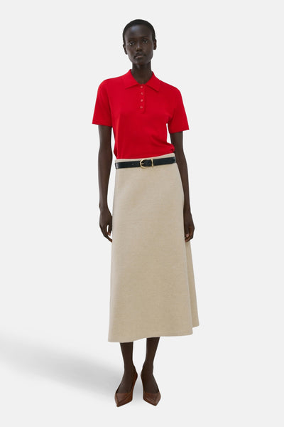 Rode polo met korte mouwen van MANGO, gedragen met een zwarte riem en een beige rok.