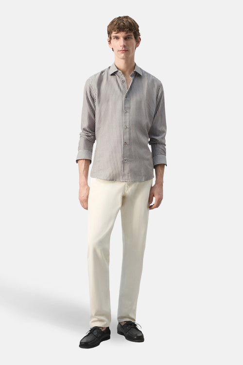 Chemise à manches longues kaki de MANGO, rayée, portée avec un pantalon beige et des chaussures bateau noires.
