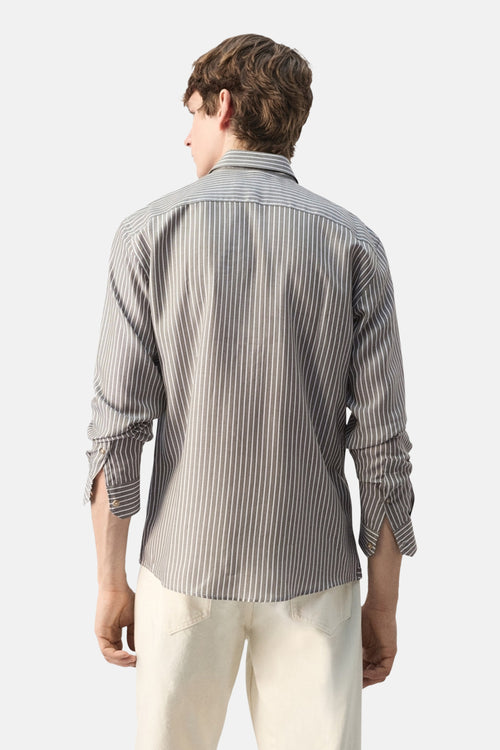 Chemise kaki à manches longues de MANGO, rayures verticales blanches, vue de dos, portée avec un pantalon beige.