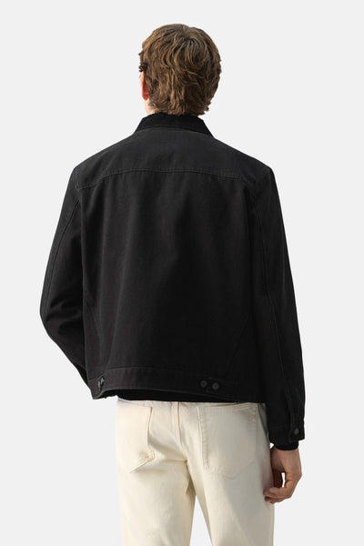 Veste courte noire de MANGO, vue de dos, portée avec un pantalon beige.