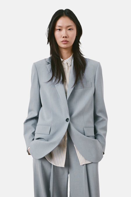 Blauwe blazer van MANGO, oversized model, gedragen door een vrouw van achteren, met bijpassende broek.