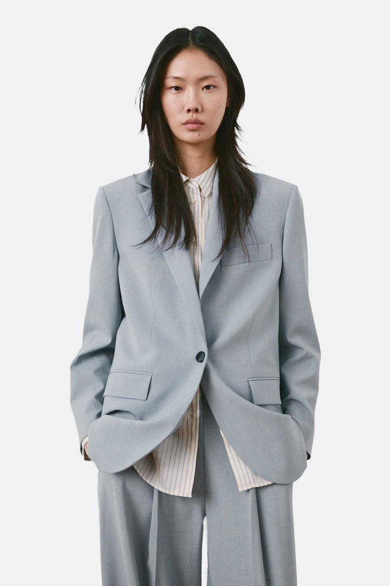 Blauwe blazer van MANGO, oversized model, gedragen door een vrouw van achteren, met bijpassende broek.