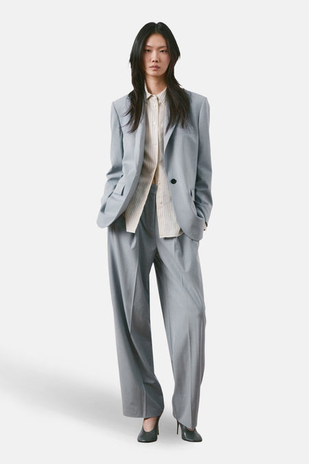 Blauwe blazer van MANGO, gedragen met een gestreept overhemd en een wijde pantalon.