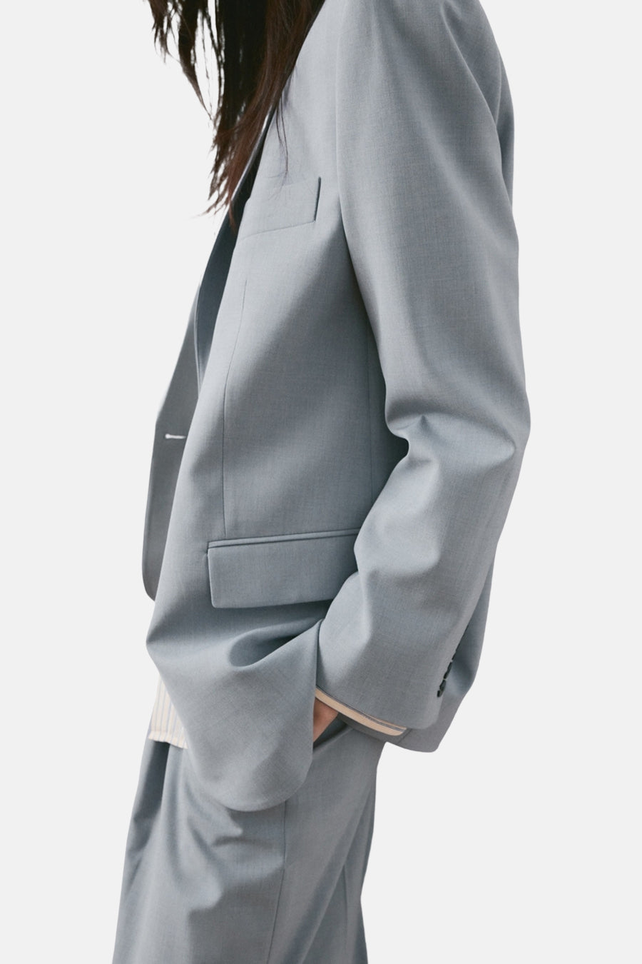 Blauwe blazer van MANGO, met een relaxte pasvorm en een gladde textuur, gedragen met een subtiel gestreept overhemd.