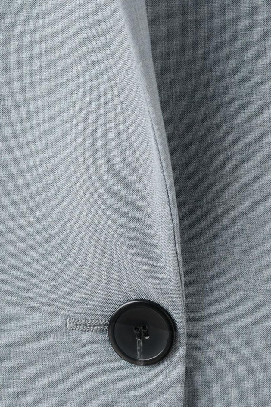 Blauwe blazer van MANGO met een subtiele textuur en een zwarte knoop.