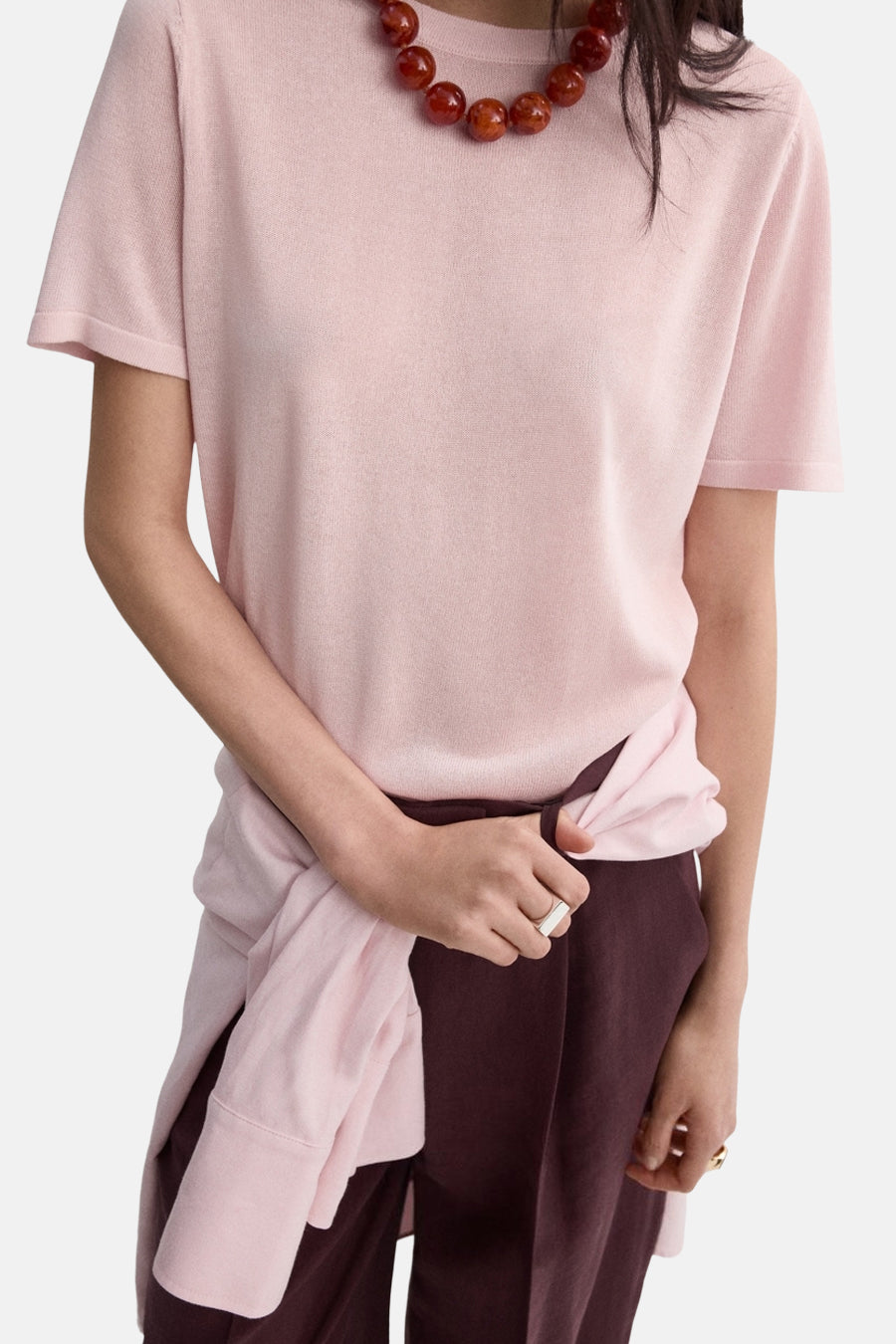 Roze trui van MANGO, gedragen met een bordeauxrode pantalon met hoge taille en rechte pijpen.