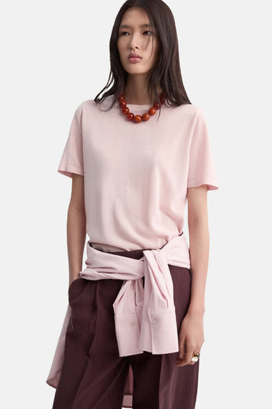 Roze gebreide trui van MANGO, gedragen met een bordeauxrode broek en een parelketting.