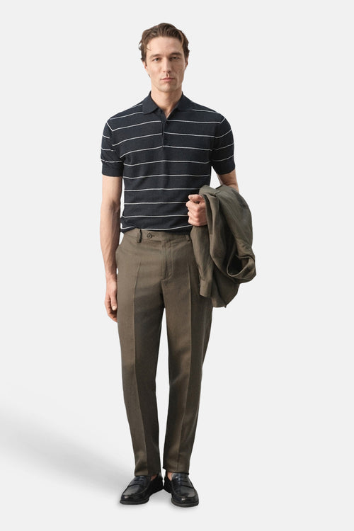 Polo noir à rayures blanches de MANGO, porté avec un pantalon marron et des chaussures noires.