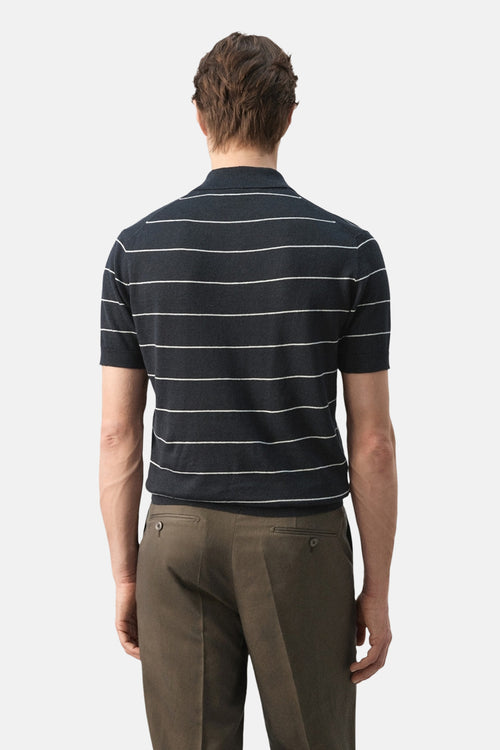 Polo noir à rayures blanches de MANGO, porté avec un pantalon marron, vue de dos.