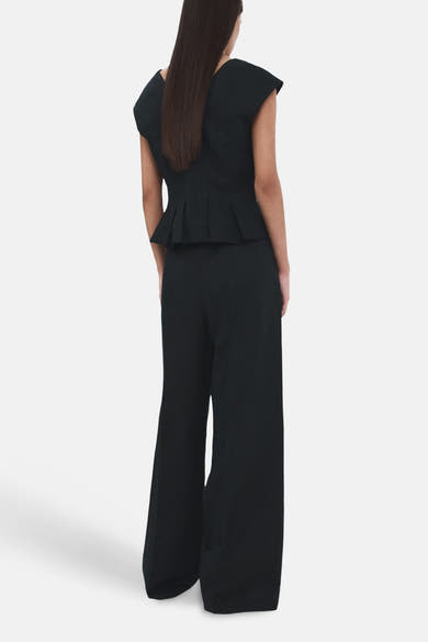 Pantalon bleu de MANGO, coupe ample, avec une texture lisse et des jambes larges, vue de dos.
