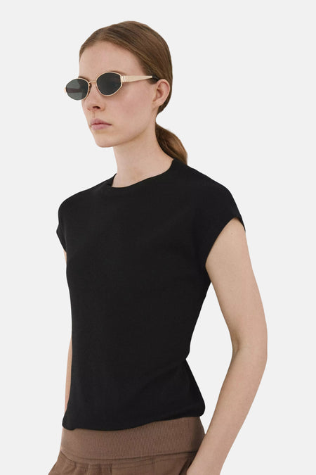 Top noir à manches courtes de MANGO, porté par une femme avec des lunettes de soleil dorées et un bas marron.