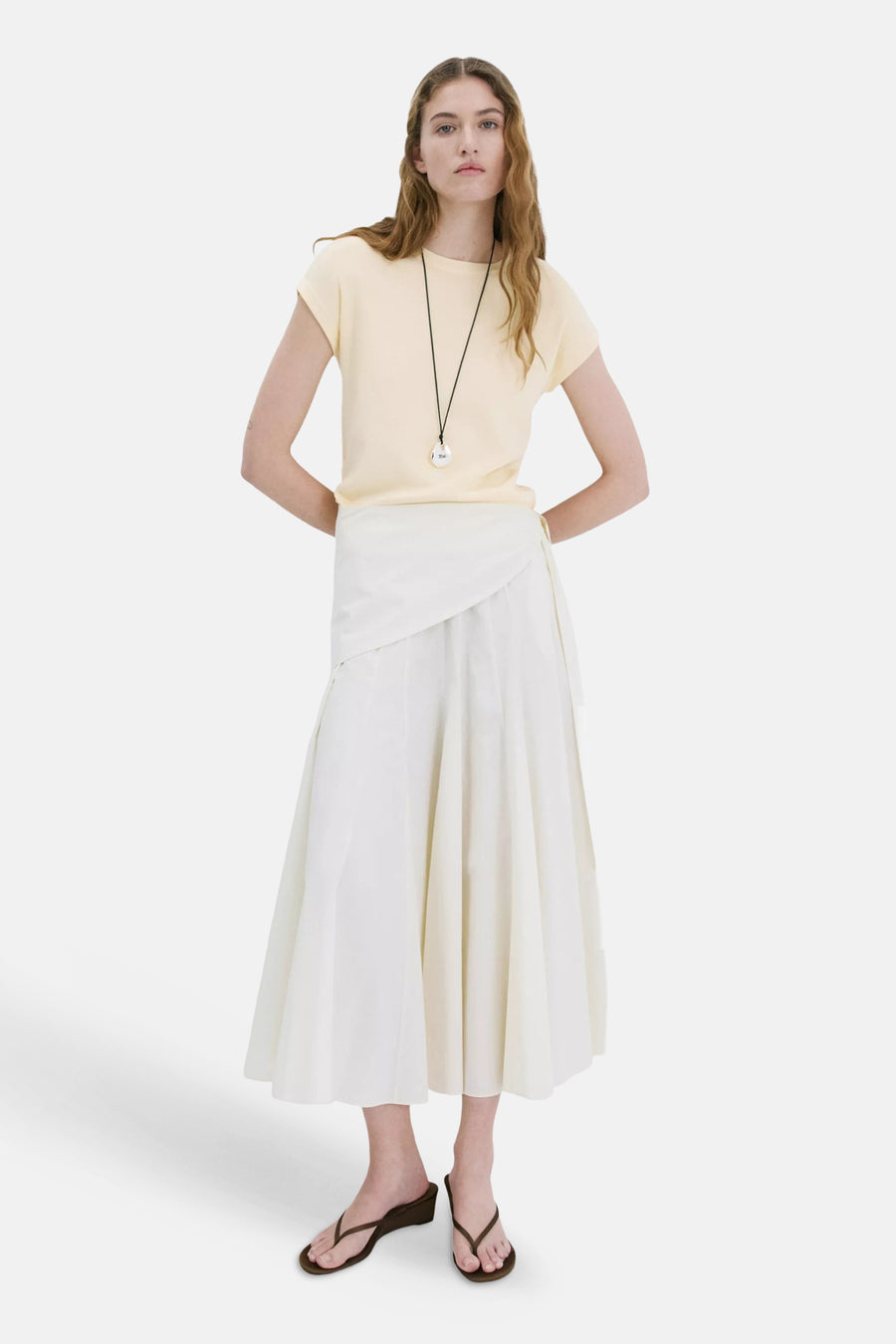Gele top met korte mouwen van MANGO, gedragen met een witte rok en sandalen.