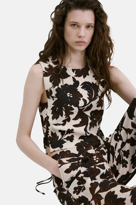Mouwloos bloesje met bruin en beige bloemenpatroon van MANGO, kort model, gedragen met een bijpassende broek.
