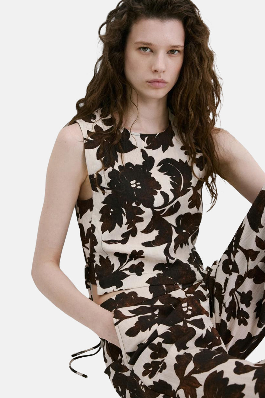 Mouwloos bloesje met bruin en beige bloemenpatroon van MANGO, kort model, gedragen met een bijpassende broek.