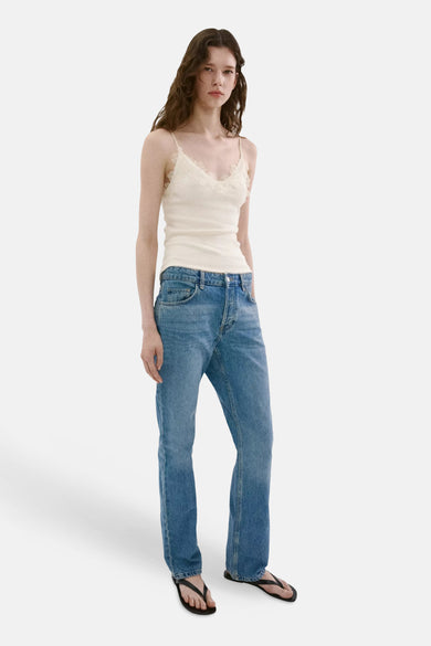 Écru ribbed tank top with lace trim neckline, worn with blue jeans and black flip-flops, front view.