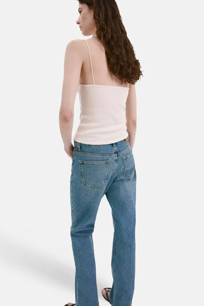 Écru ribbed spaghetti strap top from back view, featuring slim fit and smooth texture, worn with blue jeans and black sandals.