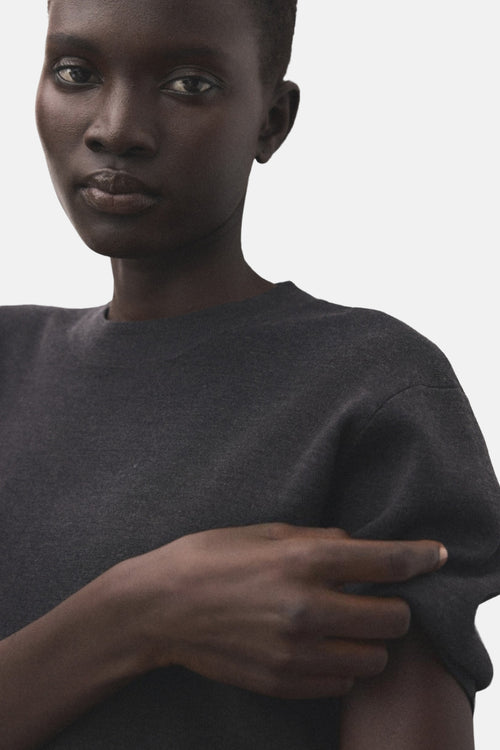 Pull à col rond gris de MANGO, détail de la texture du tissu, porté par une femme à la peau foncée.