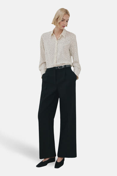 Multikleuren blouse met lange mouwen van MANGO, met stippen, gedragen met een zwarte broek met hoge taille en zwarte schoenen.