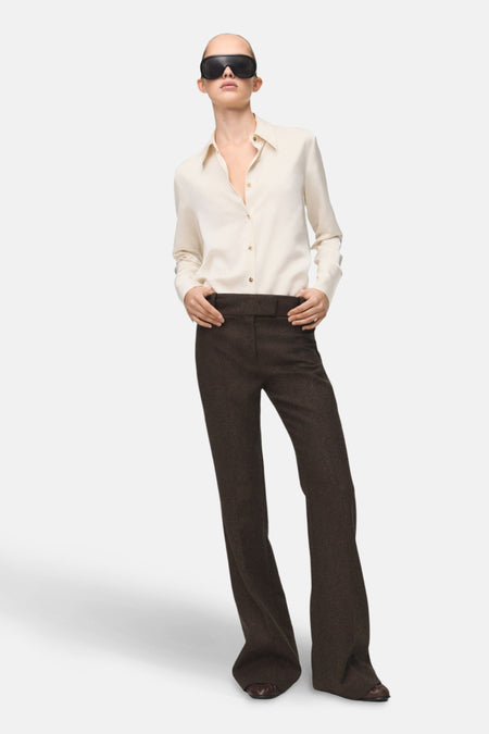 Chemise à manches longues écru de MANGO, portée avec un pantalon marron foncé et des lunettes de soleil noires.