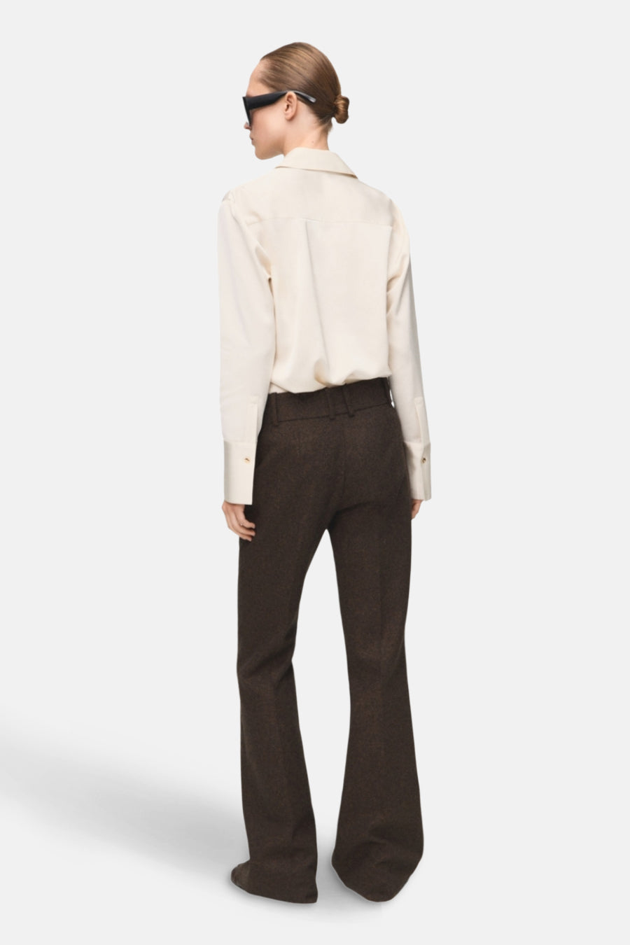 Chemise à manches longues écrue de MANGO, portée avec un pantalon marron à taille haute, vue de dos.
