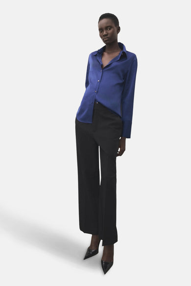 Blauw overhemd met lange mouwen van MANGO, gedragen met een zwarte pantalon met hoge taille en zwarte puntige pumps.