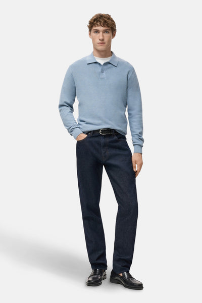 Pull à col en V bleu de MANGO, porté avec un jean foncé et des mocassins noirs.