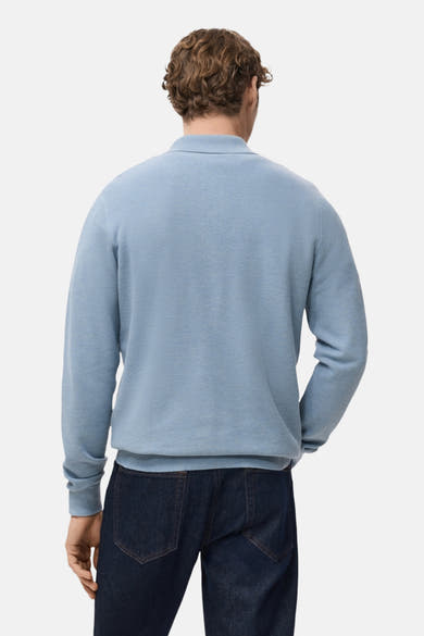 Pull à col en V bleu de MANGO, porté avec un jean bleu foncé, vue de dos.