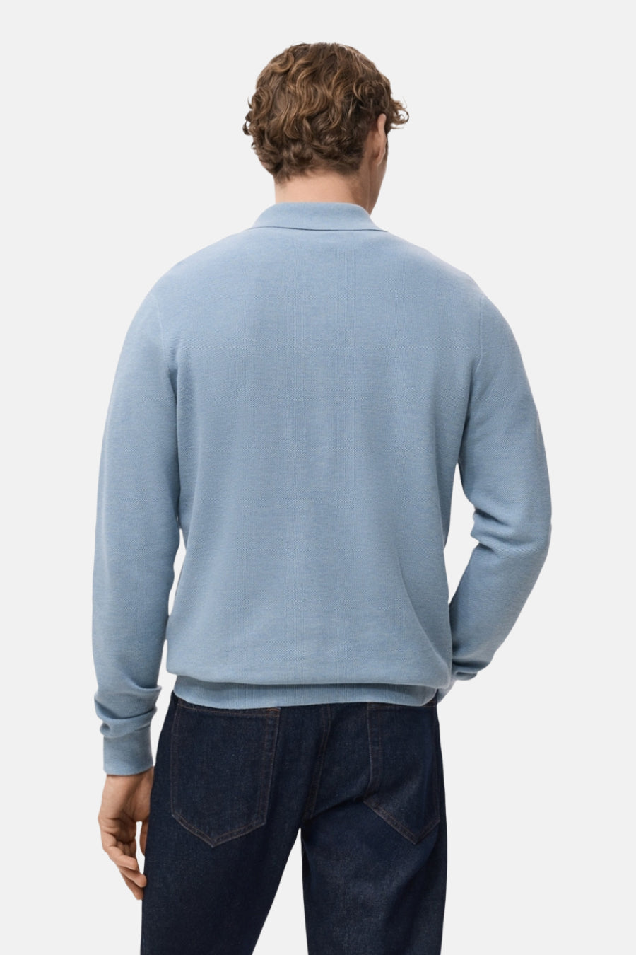 Pull à col en V bleu de MANGO, porté avec un jean bleu foncé, vue de dos.