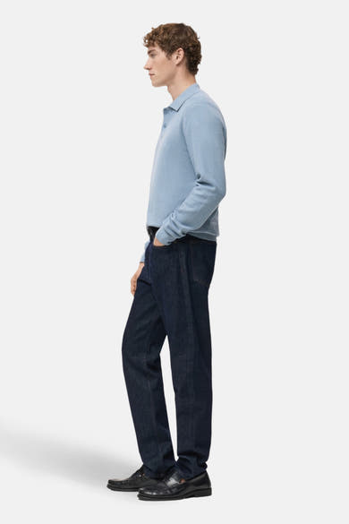 Blauwe V-hals trui van MANGO, gedragen met een donkere jeans en zwarte loafers, in zijaanzicht.