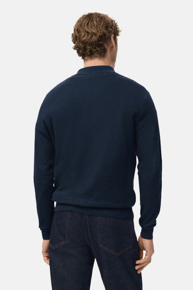 Pull à col en V bleu de MANGO, porté avec un jean bleu marine, vue de dos.
