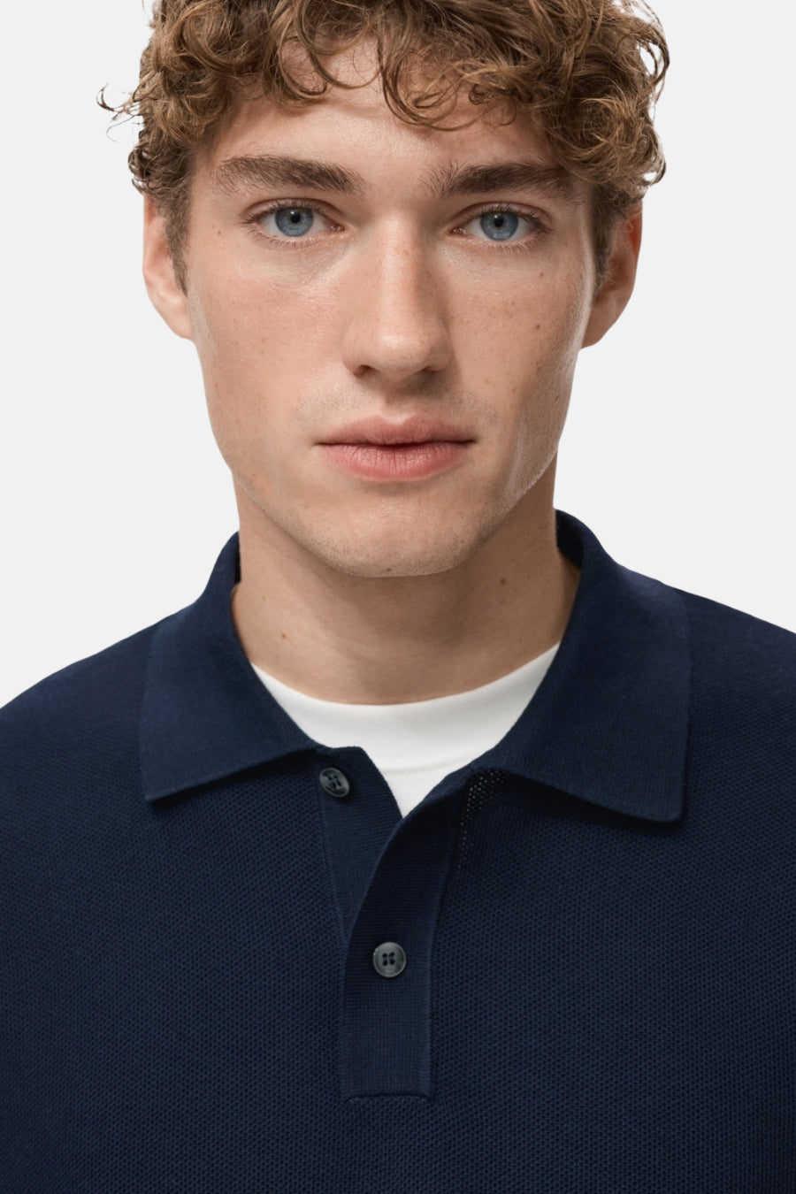 Blauwe V-hals trui van MANGO, gedragen met een wit T-shirt, close-up van de voorkant.
