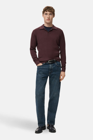 Pull à col en V bordeaux de MANGO, porté avec un jean bleu et des mocassins noirs.