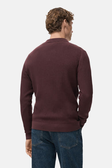 Pull à col en V bordeaux de MANGO, en maille côtelée, porté avec un jean bleu.