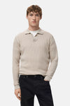 Pull col V beige de MANGO, porté avec un t-shirt blanc et un jean noir.