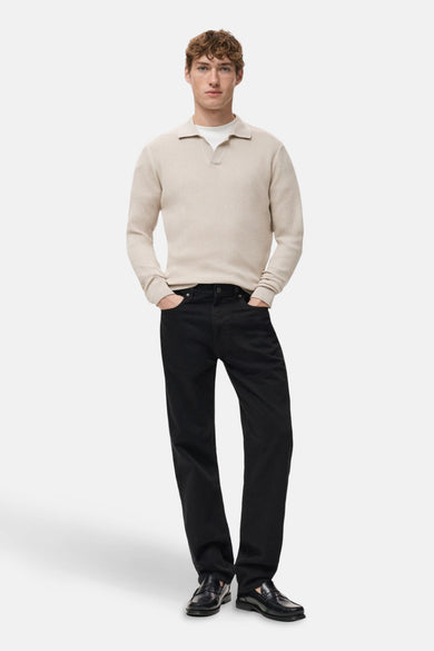 Pull à col en V beige de MANGO, porté avec un t-shirt blanc, un jean noir et des mocassins noirs.