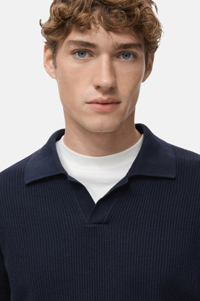 Pull col V bleu de MANGO, en maille côtelée, porté avec un t-shirt blanc.