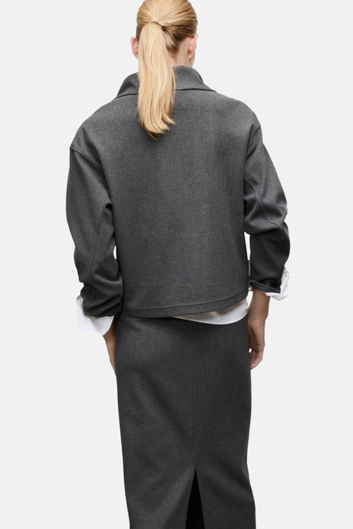 Sweat gris de MANGO, porté avec une chemise blanche et une jupe droite grise, vue de dos.
