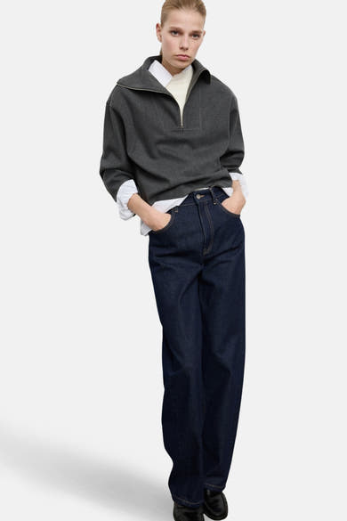 Grijze halve rits sweater, van MANGO, gedragen over een wit overhemd en een donkerblauwe jeans.