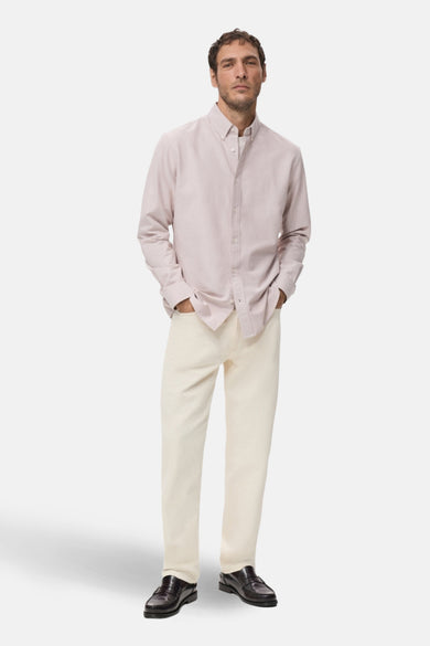 Chemise à manches longues rose de MANGO, portée avec un pantalon clair et des mocassins en cuir.