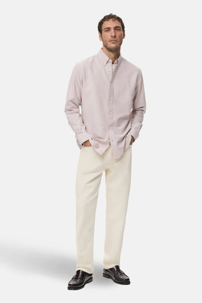 Chemise à manches longues rose de MANGO, portée avec un pantalon clair et des mocassins en cuir.