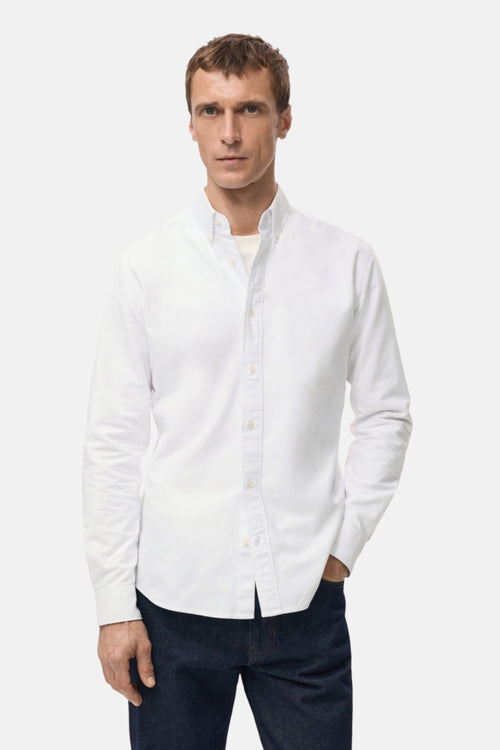 Chemise blanche à manches longues de MANGO, portée avec un jean bleu foncé et une chemise blanche.