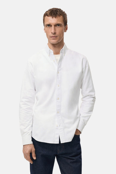 Chemise blanche à manches longues de MANGO, portée avec un jean bleu foncé et une chemise blanche.